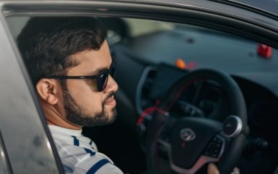 man in white and blue stripe polo shirt driving car